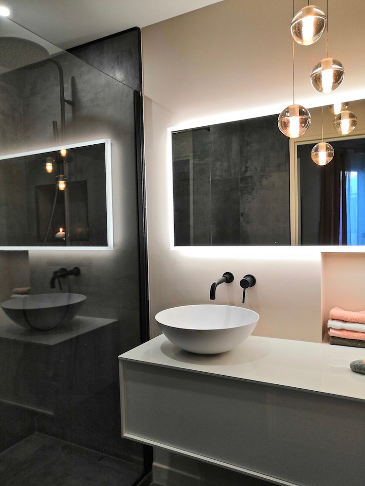 Salle de bain sombre avec vasque posée, miroir lumineux et suspensions en verre – duplex Vincennes