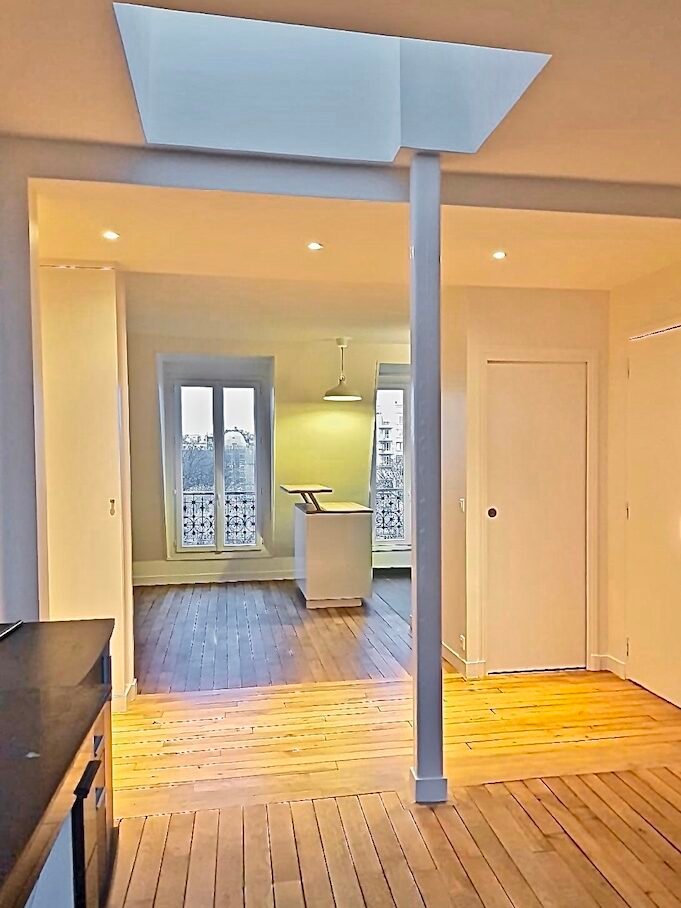 Pièce à vivre ouverte sous puits de lumière après restructuration – appartement sous combles Paris 16