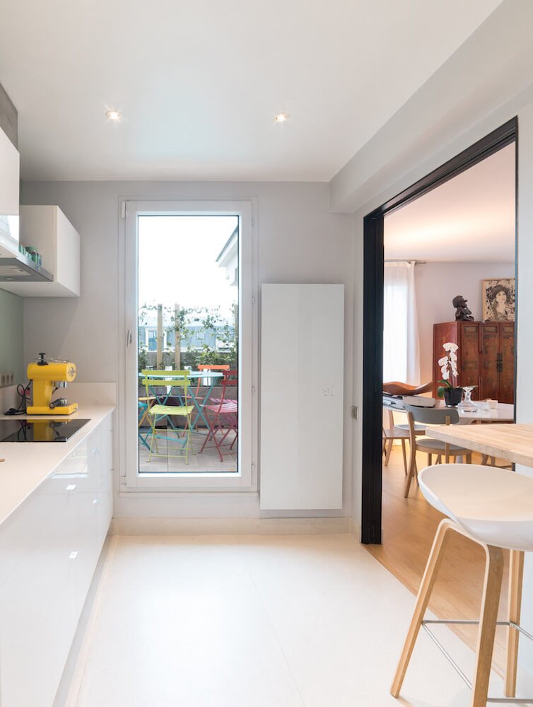 Cuisine blanche ouverte sur la terrasse après rénovation – duplex familial Vincennes