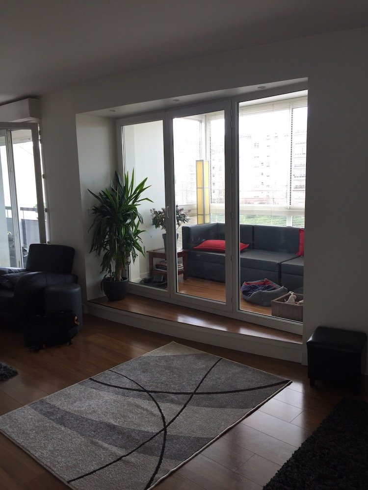 Séjour avec baie vitrée et tapis gris avant décoration – appartement Charenton-le-Pont
