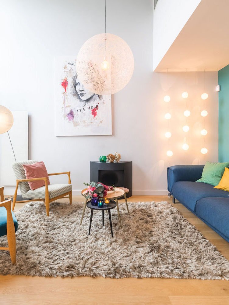 Salon lumineux avec suspension boule, tapis moelleux et canapé bleu – duplex rénové Vincennes