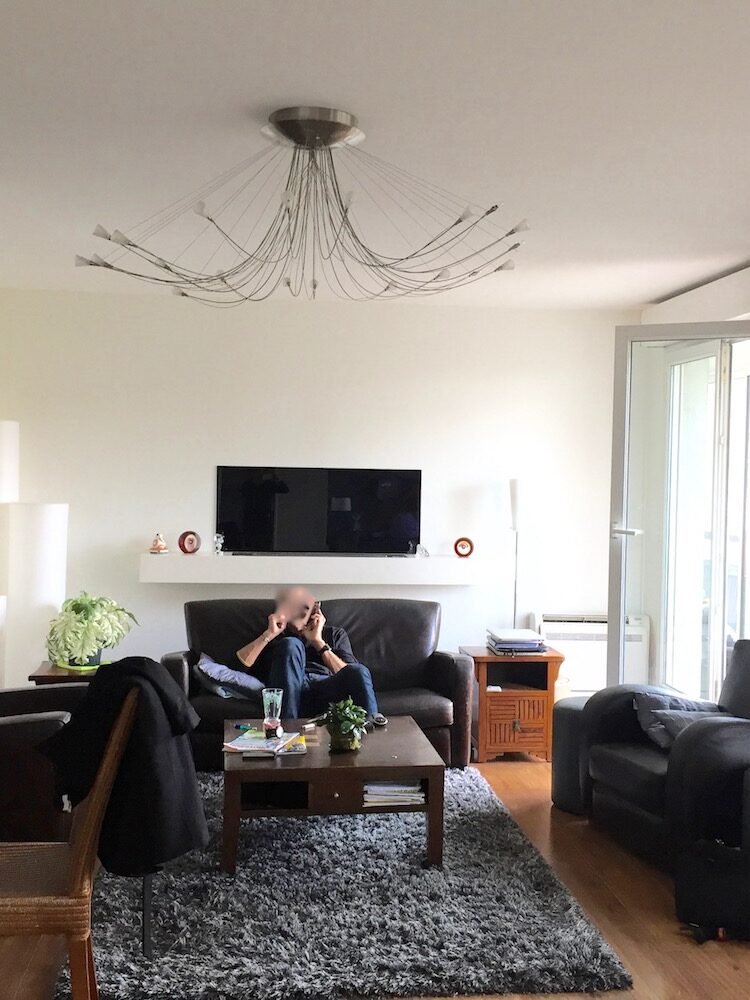 Salon avec canapé en cuir noir et tapis gris avant décoration – appartement Charenton-le-Pont