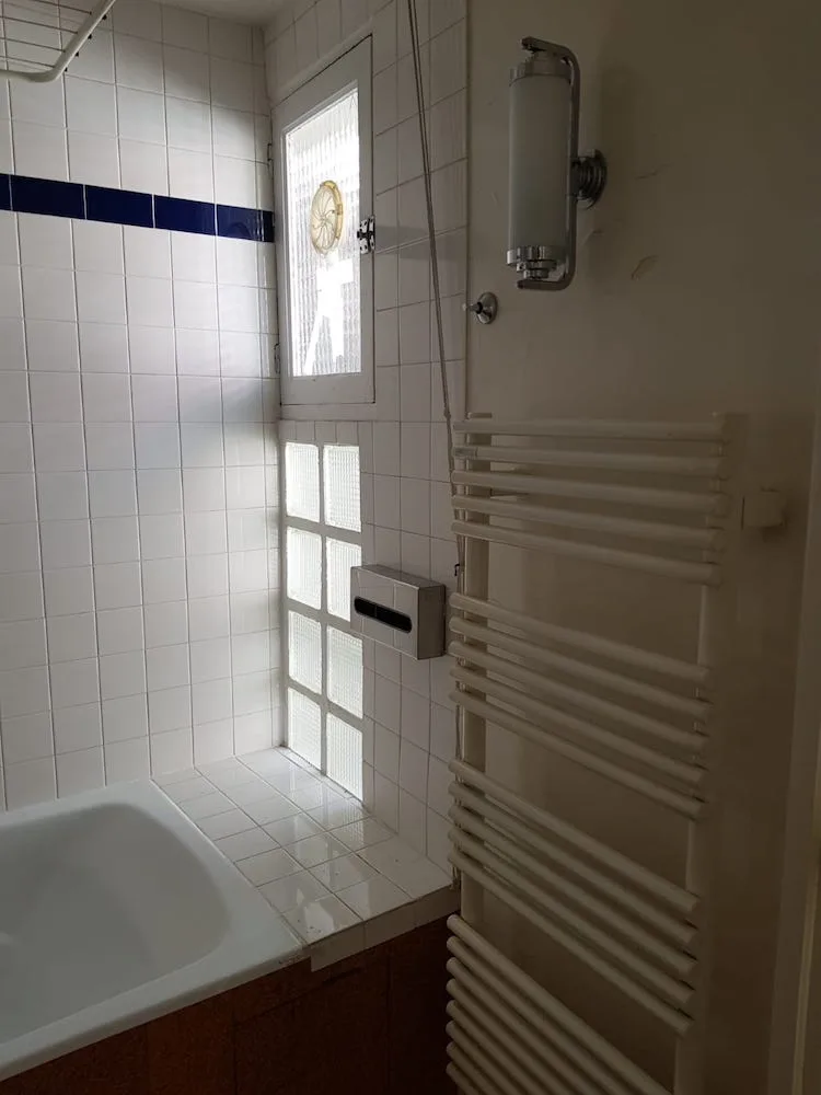 Salle de bain carrelée blanc et bleu avec baignoire avant rénovation – appartement Paris 17