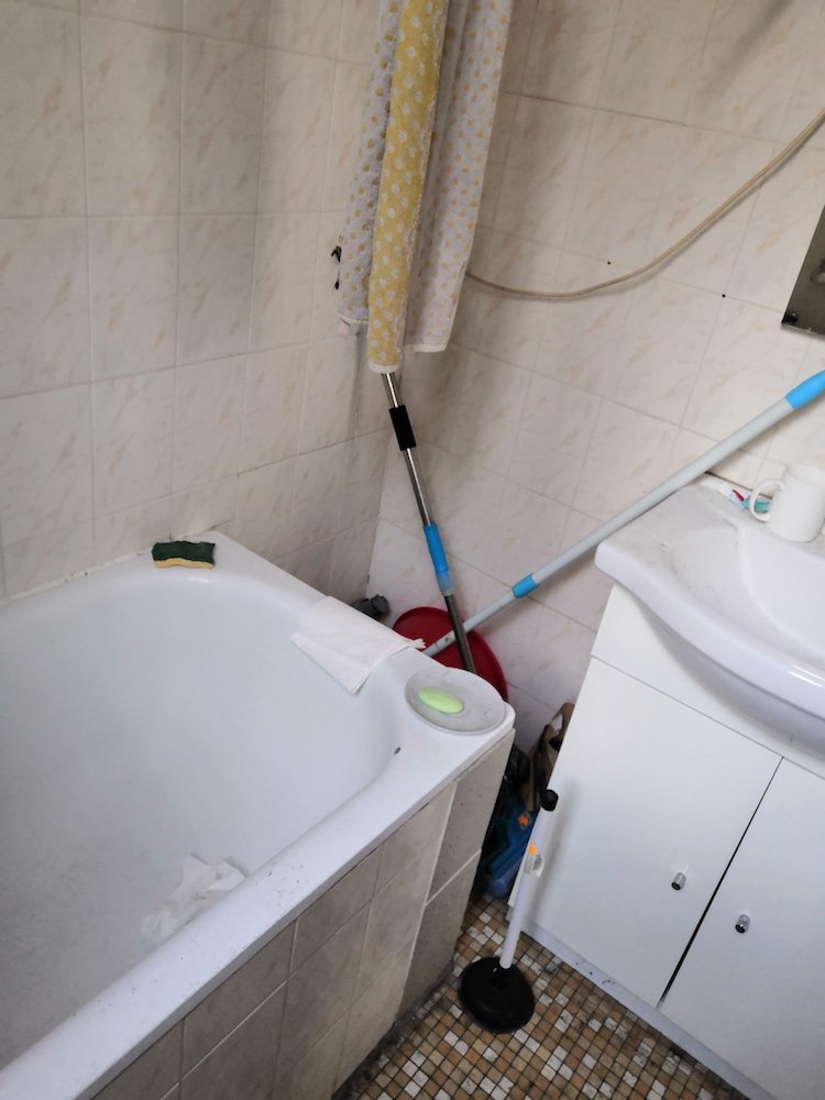 Salle de bain vétuste avec baignoire avant rénovation – studio Paris 10