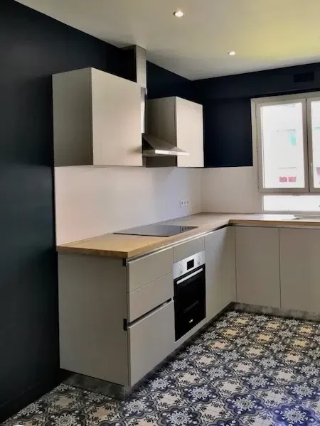 Cuisine rénovée gris perle avec plan de travail en chêne clair, murs bleu nuit et carreaux de ciment, appartement Paris 16