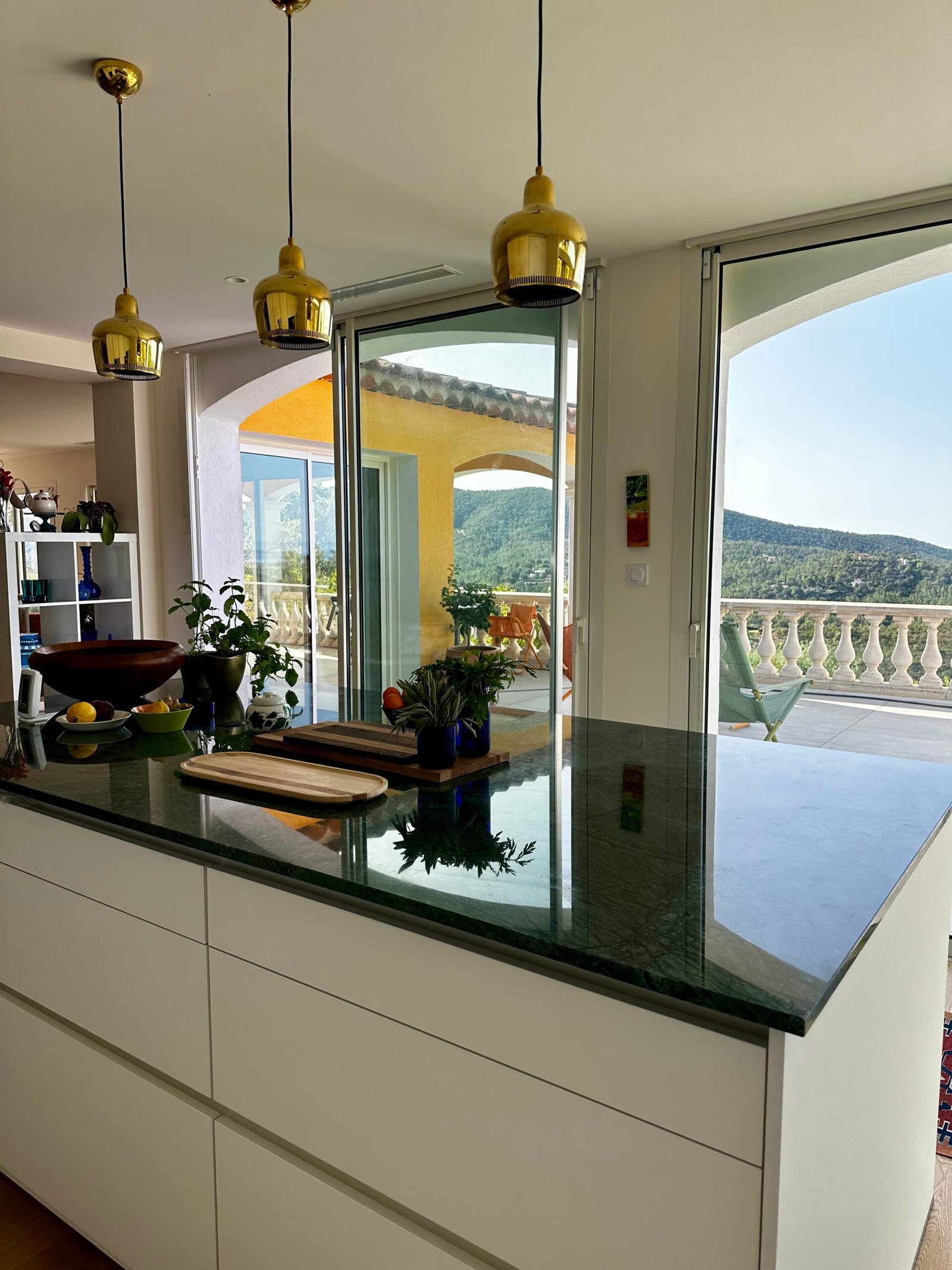 Cuisine dans l'extension avec îlot en marbre vert et baies vitrées ouvertes sur la vue – villa à Hyères