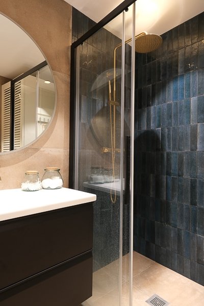 Salle de bain en zellige bleu nuit avec paroi vitrée et robinetterie laiton – appartement Paris 9