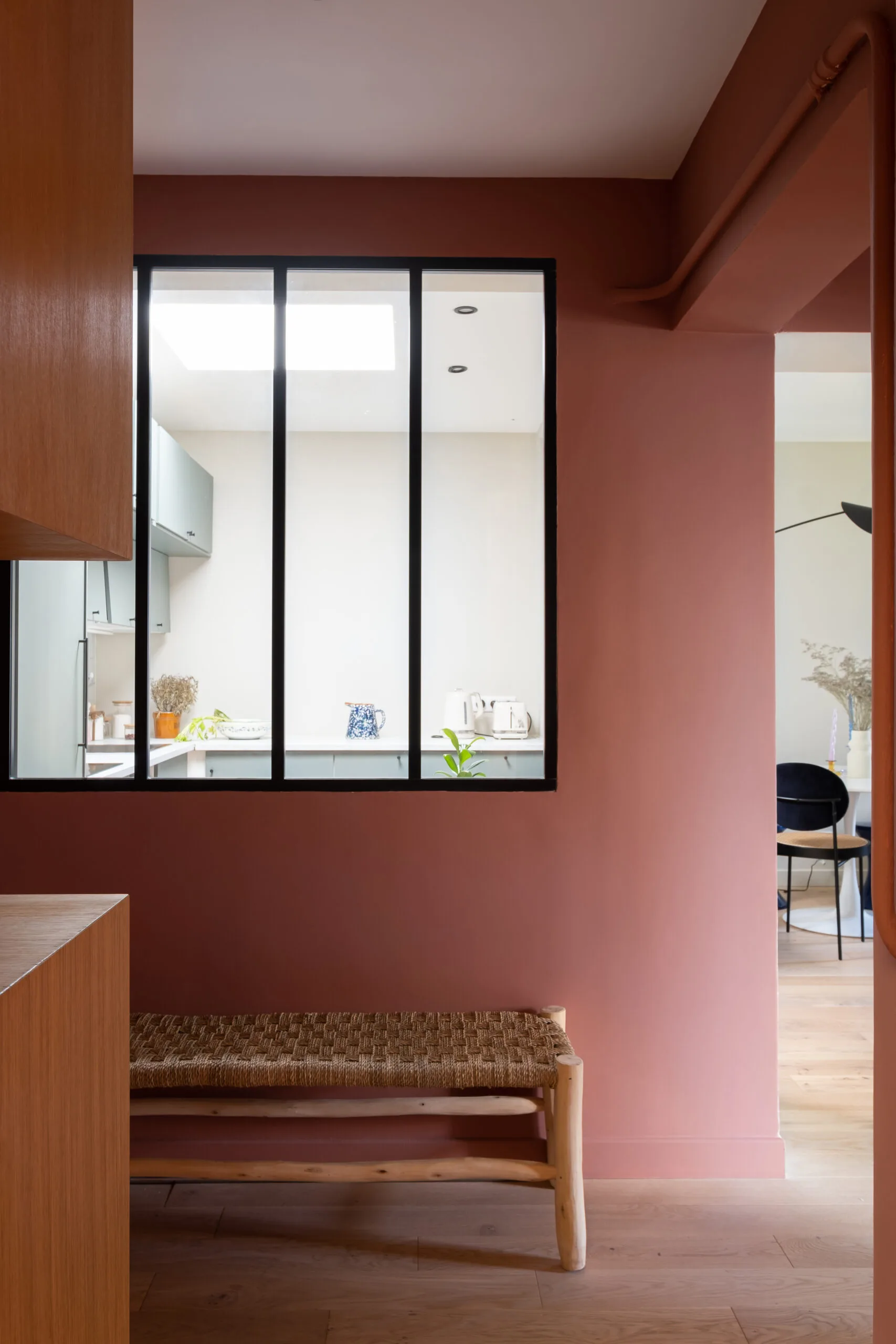 Entrée rose terracotta avec verrière d'atelier et banc en paille – appartement sous combles Paris 17