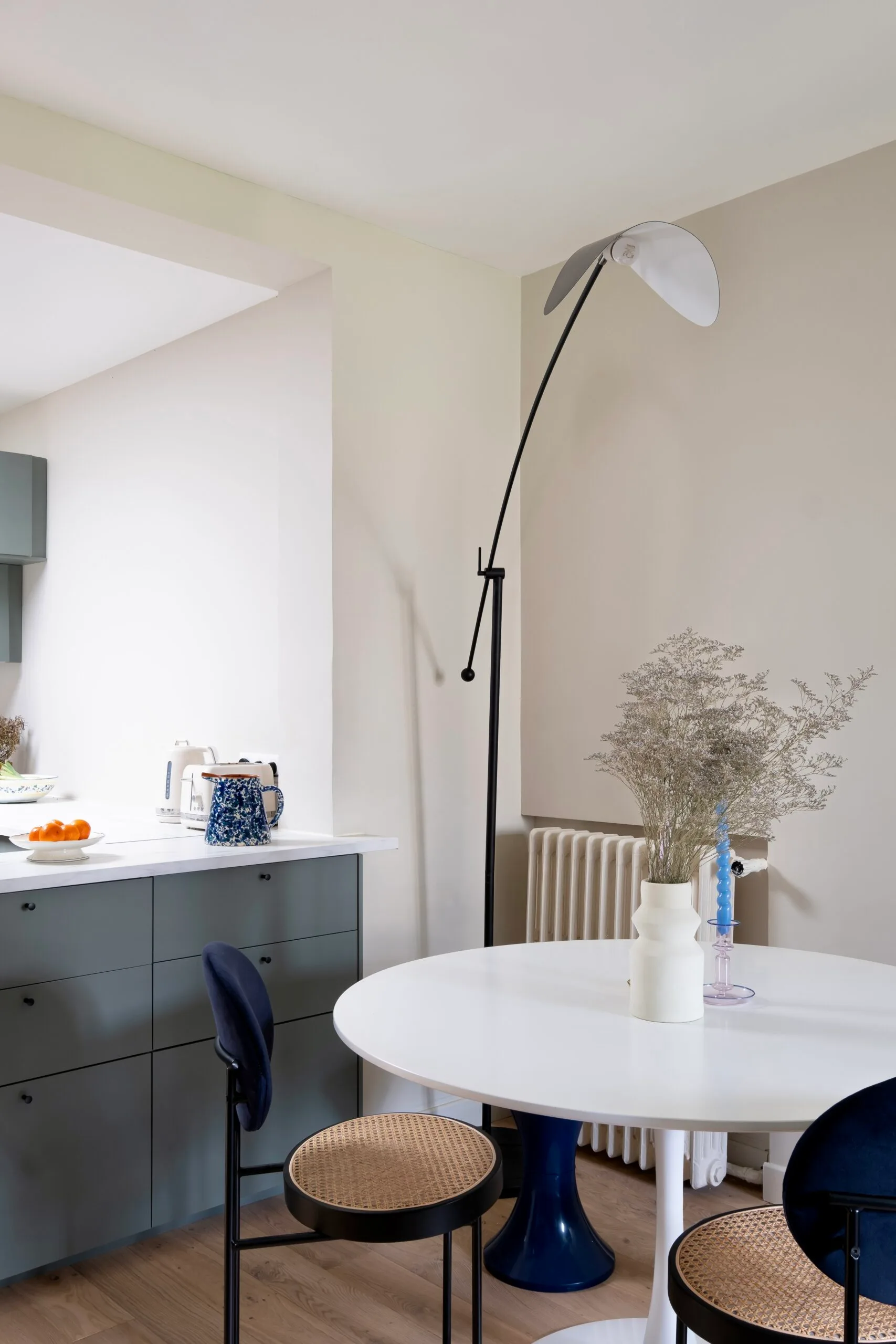 Coin repas avec table ronde blanche et cuisine vert-de-gris – appartement sous combles Paris 17