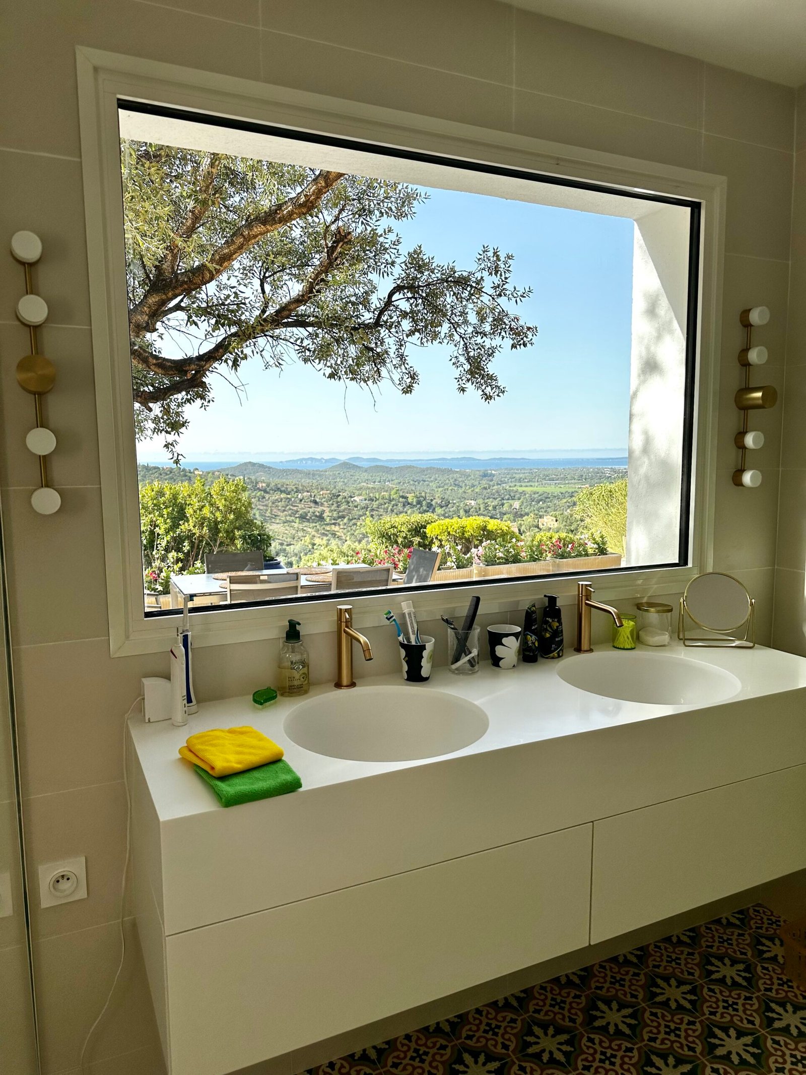 Salle de bain avec Double vasque sous une grande fenêtre avec vue mer et robinetterie laiton – salle de bain rénovée à Hyères