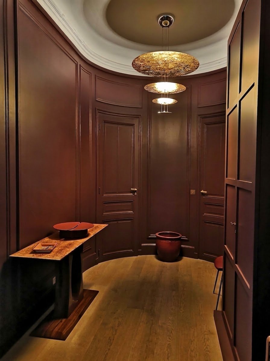 Entrée ovale aux boiseries bordeaux et suspensions dorées étagées – appartement haussmannien Paris 16