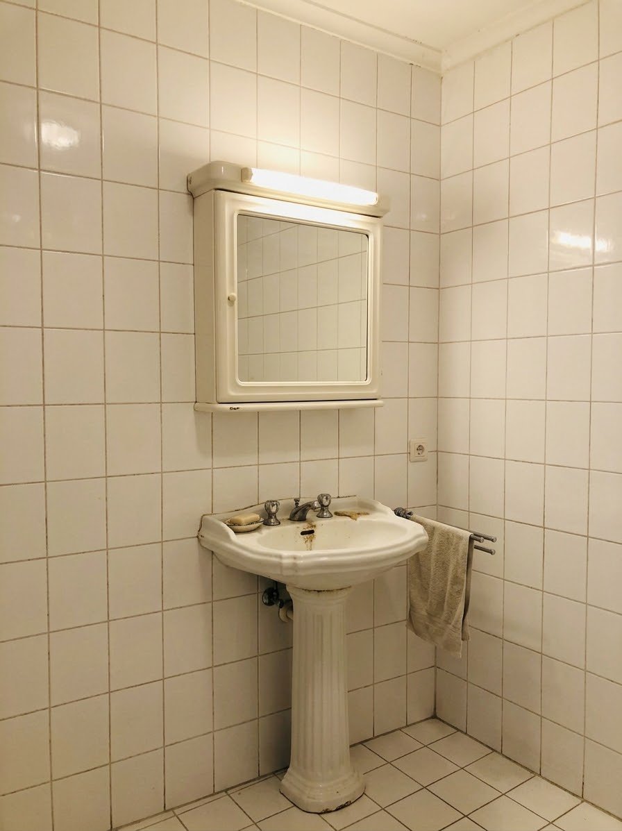 Salle de bain avant rénovation à Paris 16 : lavabo sur colonne et carrelage blanc