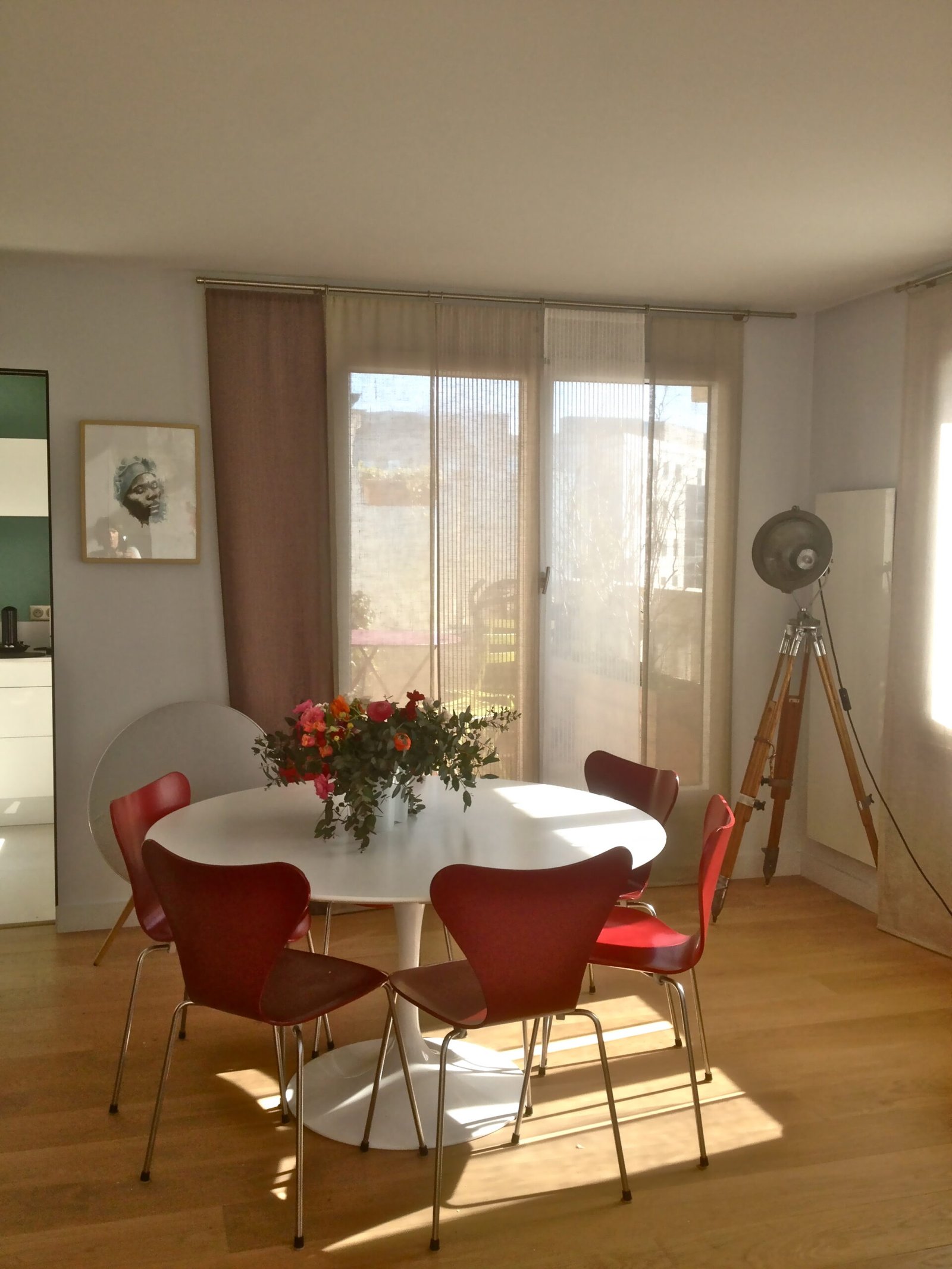 Salle à manger avec table ronde blanche et chaises rouges – appartement rénové Paris 13
